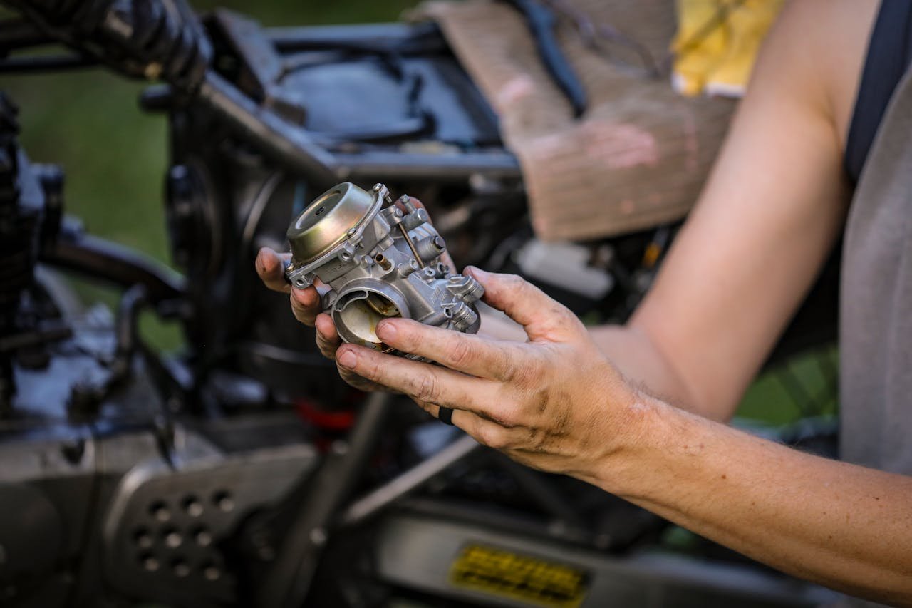 our-services-3 Close-up of hands holding a motorcycle carburetor, ideal for automotive repair visuals.