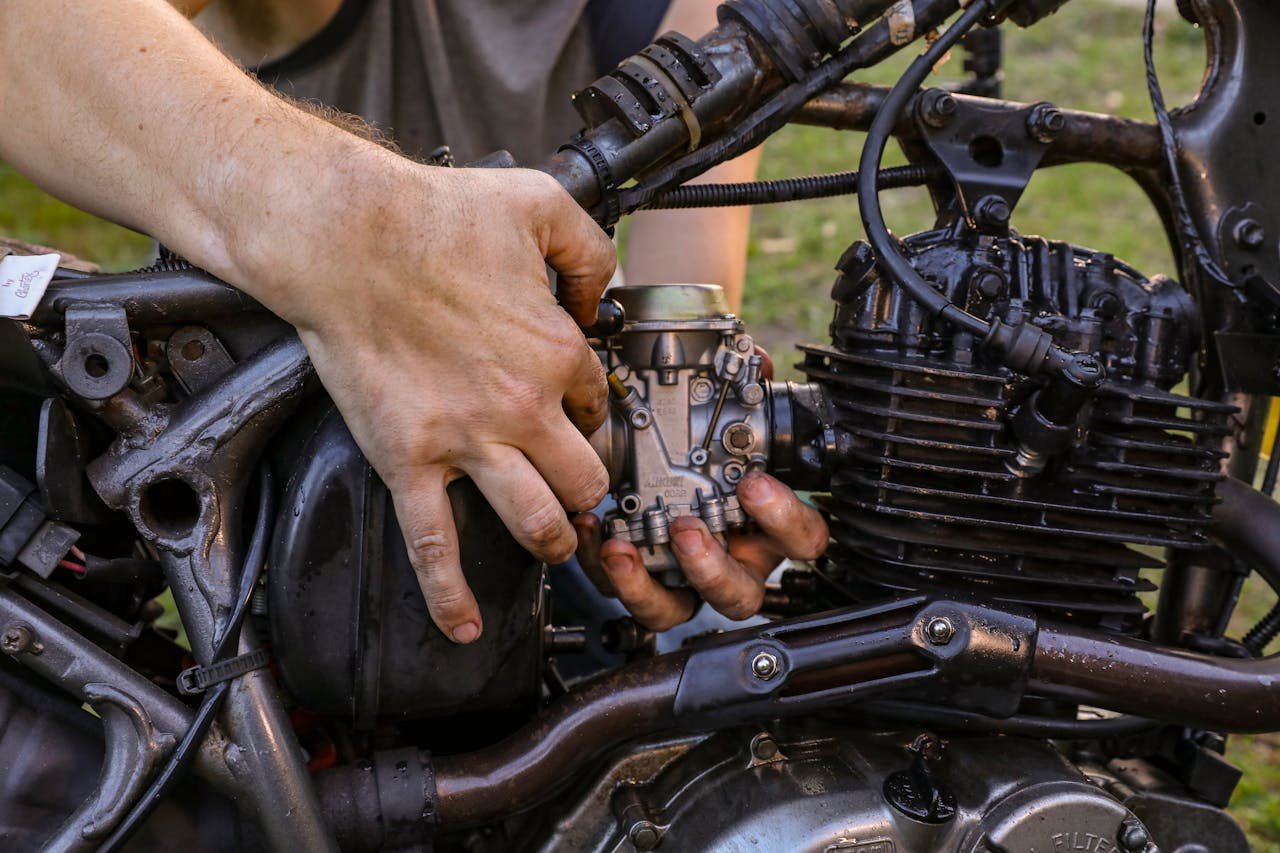 why-choose-us Close-up of a mechanic's hands fixing a motorcycle engine outdoors, showcasing expertise in engine repair.
